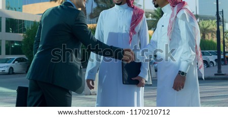 Middle eastern and caucasian businessmen shaking hands outdoor on a sunny day Royalty-Free Stock Photo #1170210712