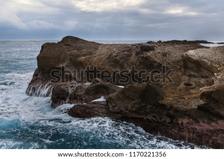 Coral reef formations with crashing turbulent blue ocean waves in the foreground. Taiwan East Coast Rocky Coastline Background Image - Overcast Skies, Exotic Rock Formations, late afternoon sunset