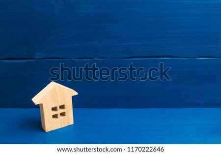 A small wooden house stands on a blue background. The concept of buying and selling real estate, renting. Search for a house. Affordable housing, credit and loans. Investments in business