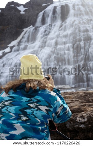 Young woman taking a photo of the Djandi water falls in Iceland