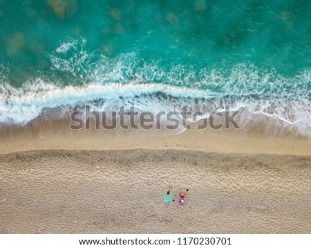 Aerial view of the amazing idyllic beach with two lonely people near waved sea.