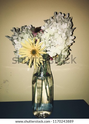 Yellow pastel flowers in a glass bottle
