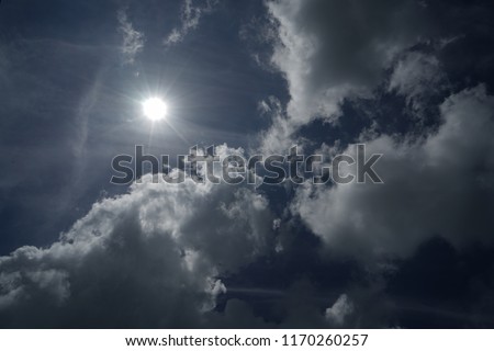 The sun shines on a white cloud in the blue sky 
