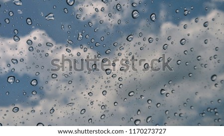 Rain drops, water drops of rain on a window glass. blurred lights city with sky clouds in rainy day.