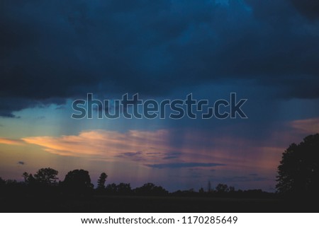 a sunset and rain in the distance