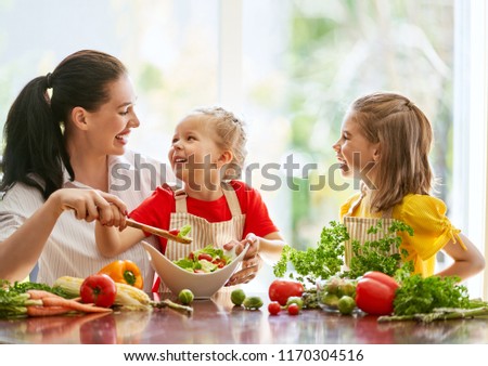 Healthy food at home. Happy family in the kitchen. Mother and children daughters are preparing the vegetables.