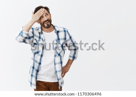 Phew, almost got in trouble. Portrait of relieved good-looking happy male breathing air out and whiping sweat from forehead while smiling broadly and gazing up, walking under hot sun over grey wall Royalty-Free Stock Photo #1170306496