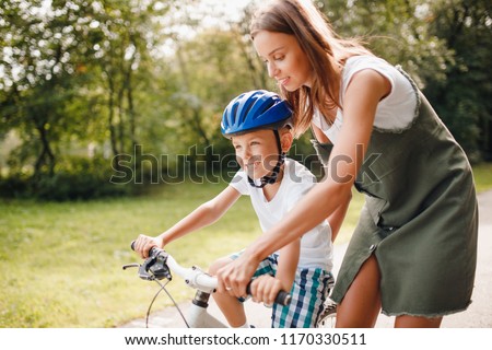 Sister and little brother learning to ride bicycle park having fun together