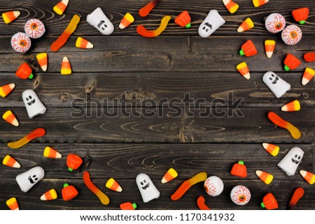 Halloween candy frame over a dark black wood background. Copy space.
