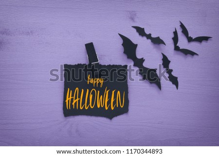 Halloween holiday minimal top view image of letter with text HAPPY HALLOWEEN over wooden purple background. Card and invitation concept
