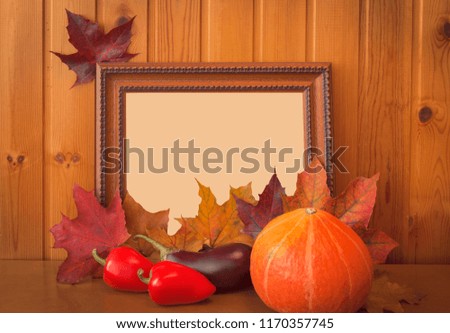 Fresh vegetables, autumn maple leaves and picture frame on wooden background