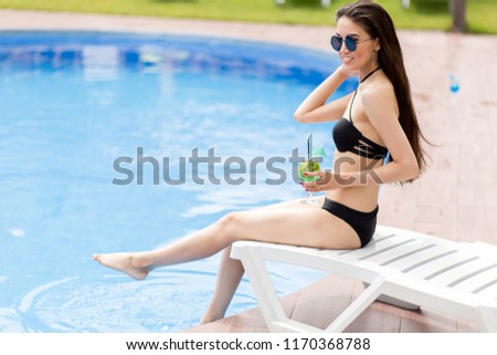 cheerful black-haired girl splashing with legs in the pool water .side view photo.have fun.amusement by the pool