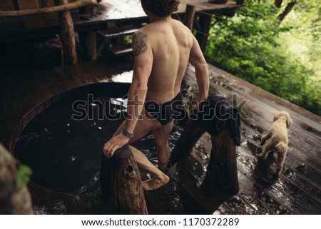 back view photo. man is going to dive into the wooden bathtub. refreshment concept. water procedure