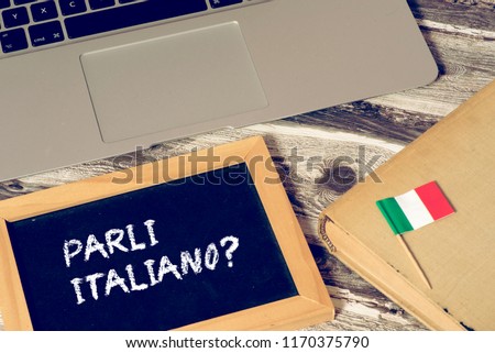 Computer, book and chalk board with the Italian translation for Do you speak Italian