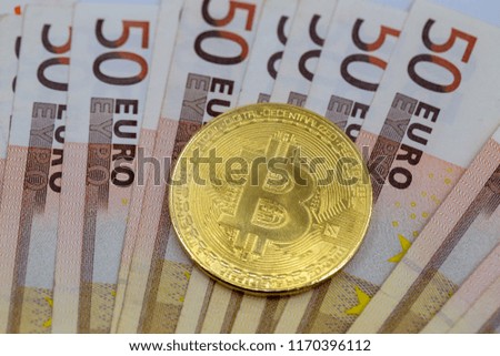 Bitcoin token on top of 50 euro banknotes money. Cryptocurrency versus paper currency concept, flat lay view