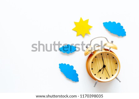 Time of day. Morning. Awakening and sunrise. Sun and clouds cutout near alarm clock on white background top view copy space