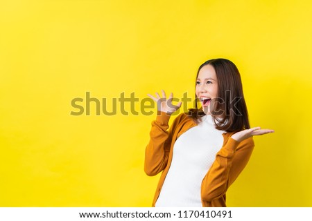 Asian girl is surprised she is excited.Yellow background studio Royalty-Free Stock Photo #1170410491