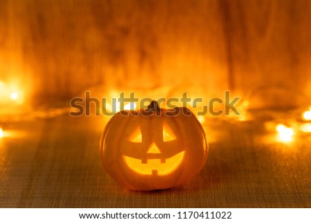 Halloween pumpkin in the middle of the picture. There are lights on the back.