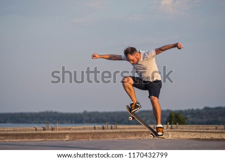 Skateboarder doing an ollie trick on background of blue sky. Active lifestyle.