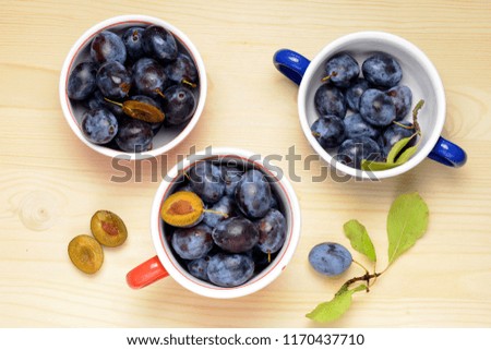 Fresh plums with leaves on a wooden table background. Flat lay composition.