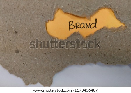 The text brand appearing behind torn brown paper.