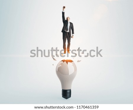 Businessman launching from abstract broken lamp. Gray background. Startup and success concept
