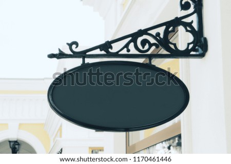 Empty black oval poster on building with classical architecture and daylight. Mock up 