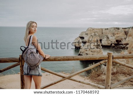 Young beautiful woman hipster traveler looking at sunset and beautiful seascape with a lookout point. Freedom, travel, vacation