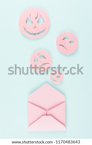 Halloween mock up with open envelope and spooky faces emoji as message of cut paper on pastel trendy mint  blue background.