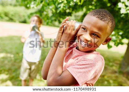 African boy with tin can telephone playing with friend Royalty-Free Stock Photo #1170498931