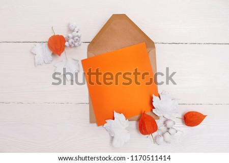 Empty orange sheet of paper flat lay mockup for your art, picture or hand lettering composition copy space, top view. Autumn composition made of white leaves on white wooden backgound