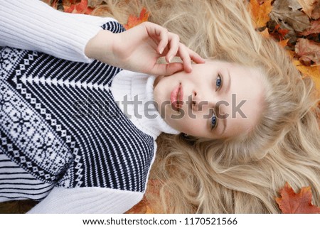 beauty, people, season and health concept - pretty girl is lying in yellow red Autumn leaves
