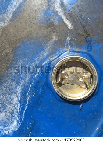 Grunge texture. The blue metal surface of the barrel with the old paint and hole. Dirty background of cracked paint.