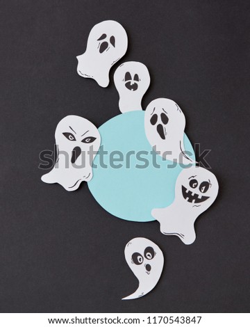 Greeting card, creative application with handmade paper terrible spirits smiling and laughing ghosts on a black background, place under text. Halloween concept. Flat lay.