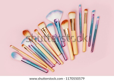 Fashion various makeup brushes on a pastel pink background. Flat lay, top view