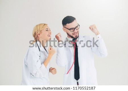 Happy successful doctor celebrates victory in hospital office with another doctor standing beside her for the success of patient treatment.