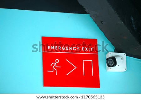 Fire emergency exit sign on a green wall.with closed-circuit television