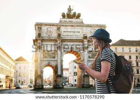 A tourist girl with a backpack looks sights in Munich in Germany. Passes by the triumphal arch. Royalty-Free Stock Photo #1170578290