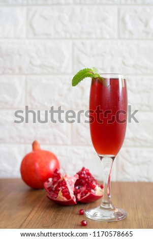 Glass of pomegranate juice with fruit on wooden table with bricks background