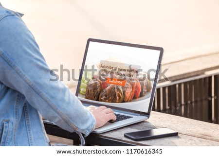A man is working using laptop doing subscribe for food blog on screen at outdoor