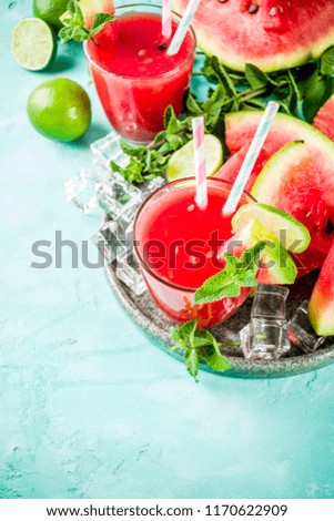 Fruity summer cold drink, homemade watermelon juice or smoothie served with lime and fresh mint leaves, light blue trendy background copy space