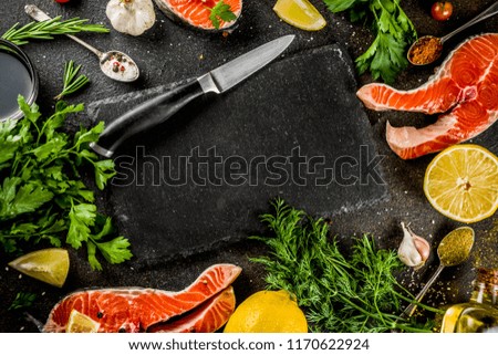 Raw salmon fish steaks with lemon, herbs, olive oil, ready for grill, slate cutting board, dark rusty background copy space
