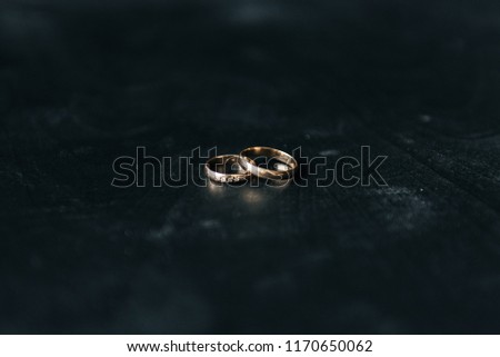 Black and white picture of wedding rings lying on dark wooden table