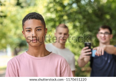 Bullied African-American teenage boy outdoors Royalty-Free Stock Photo #1170651220