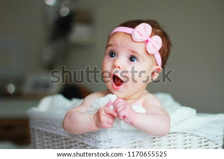 Cute baby girl, with a bow on her hair, with amazement face