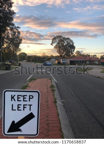 Keep Left Street Sign in Residential neighbourhood agains setting sun