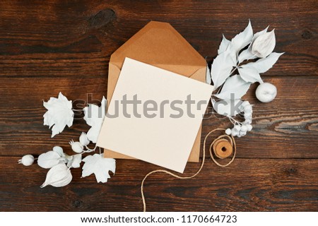 Empty kraft sheet of paper with pensil flat lay mockup for your art, picture or hand lettering composition copy space, top view. Autumn composition made of white leaves on dark brown wooden backgound