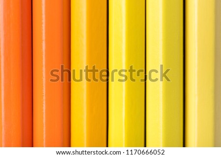 Macro photograph of several sharpened pencils of yellow and orange color on a white background
