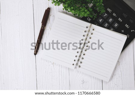 Fountain pen or ink pen with notebook paper and calculator on wooden working table with copy space, office desk concept idea. top view.