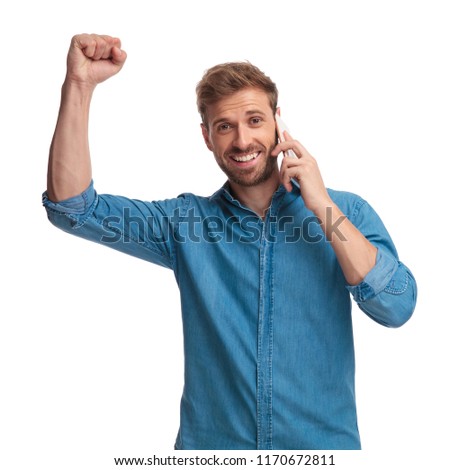 excited young casual man celebrating good news on the phone on white background